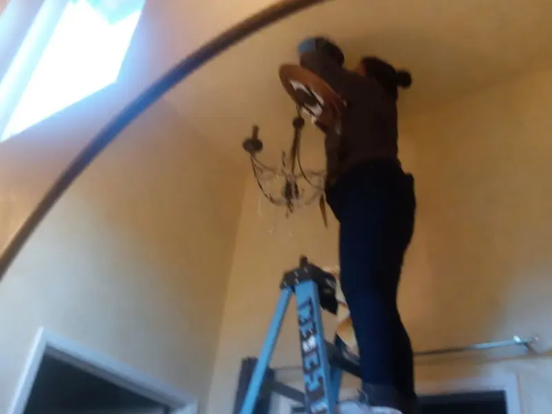 Electrician installing a chandelier in a Rifle residence
